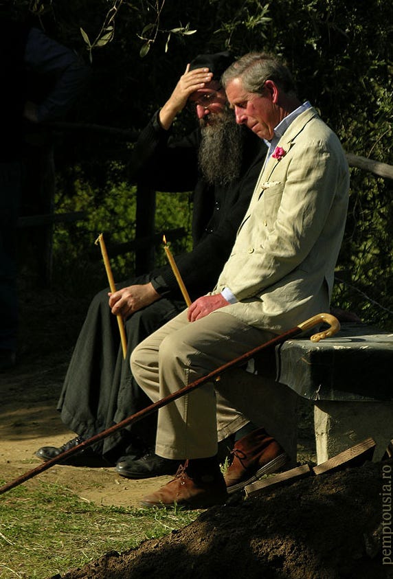 What appears to be an Orthodox priest with King Charles, sitting on a bench holding candles. 